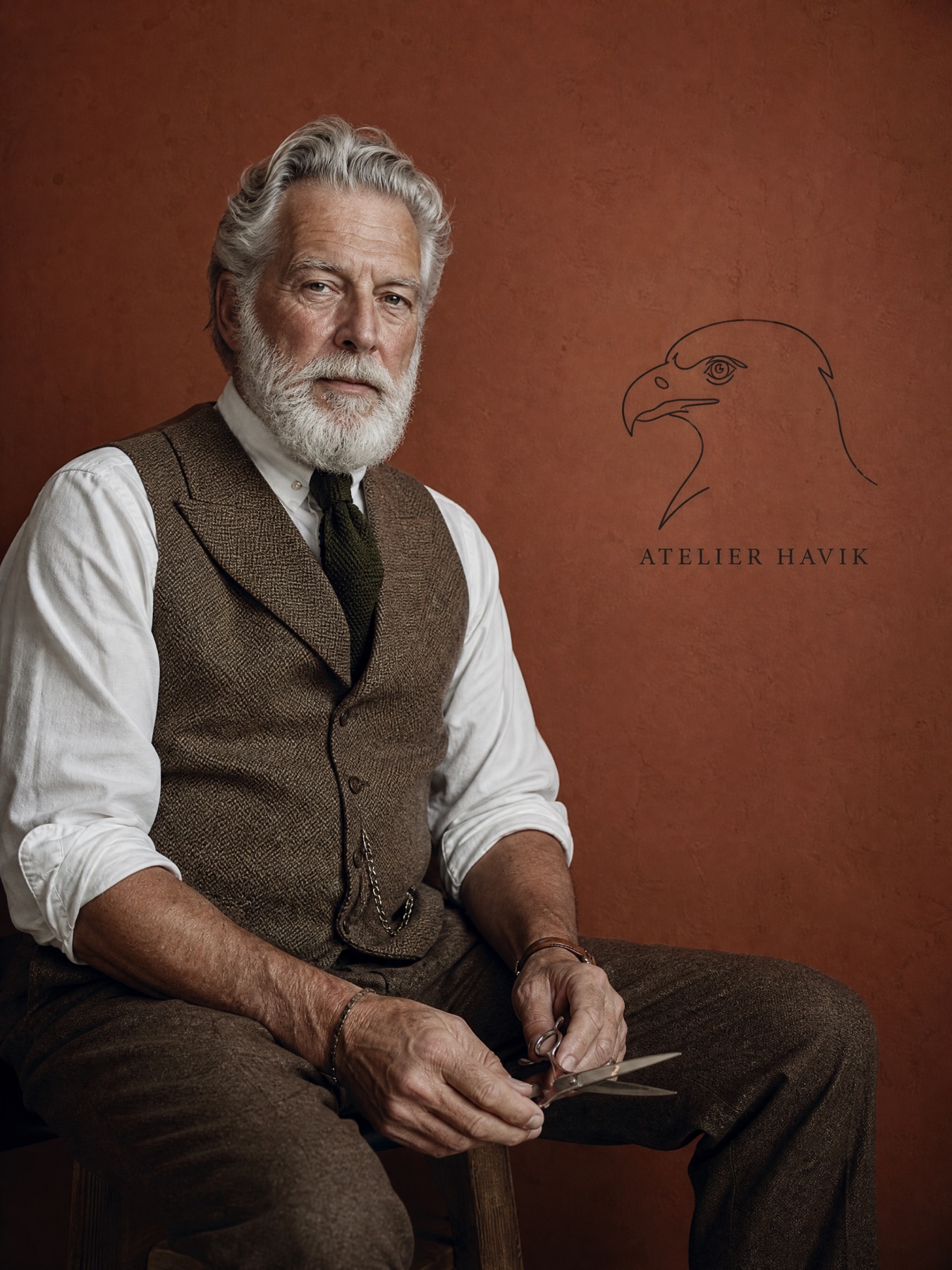 Meester-barbier van Atelier Havik in tweed vest, het havik-monogram op de wand