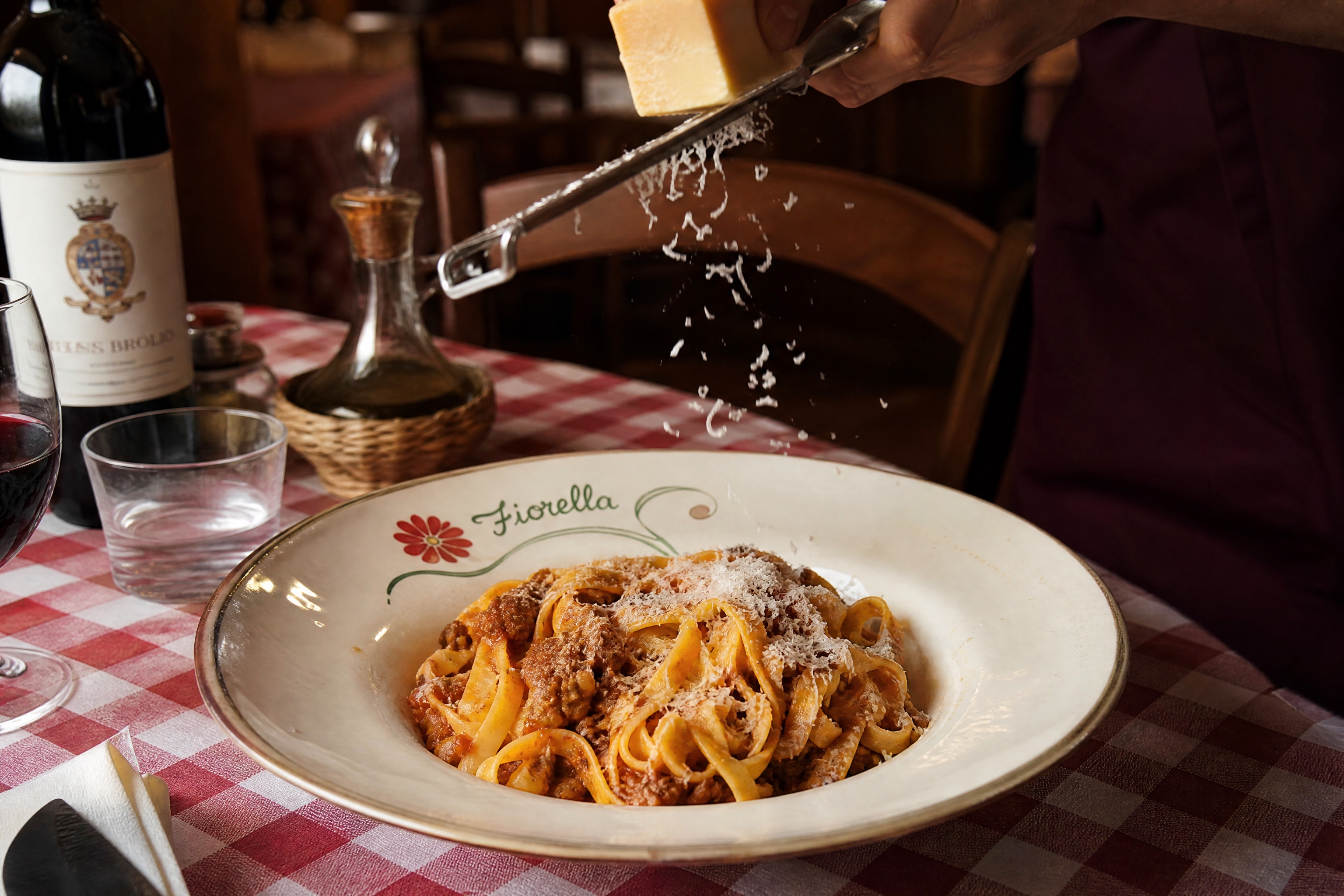 Tagliatelle al ragù op het geruite kleed, het bordje handbeschilderd met de Fiorella-bloem