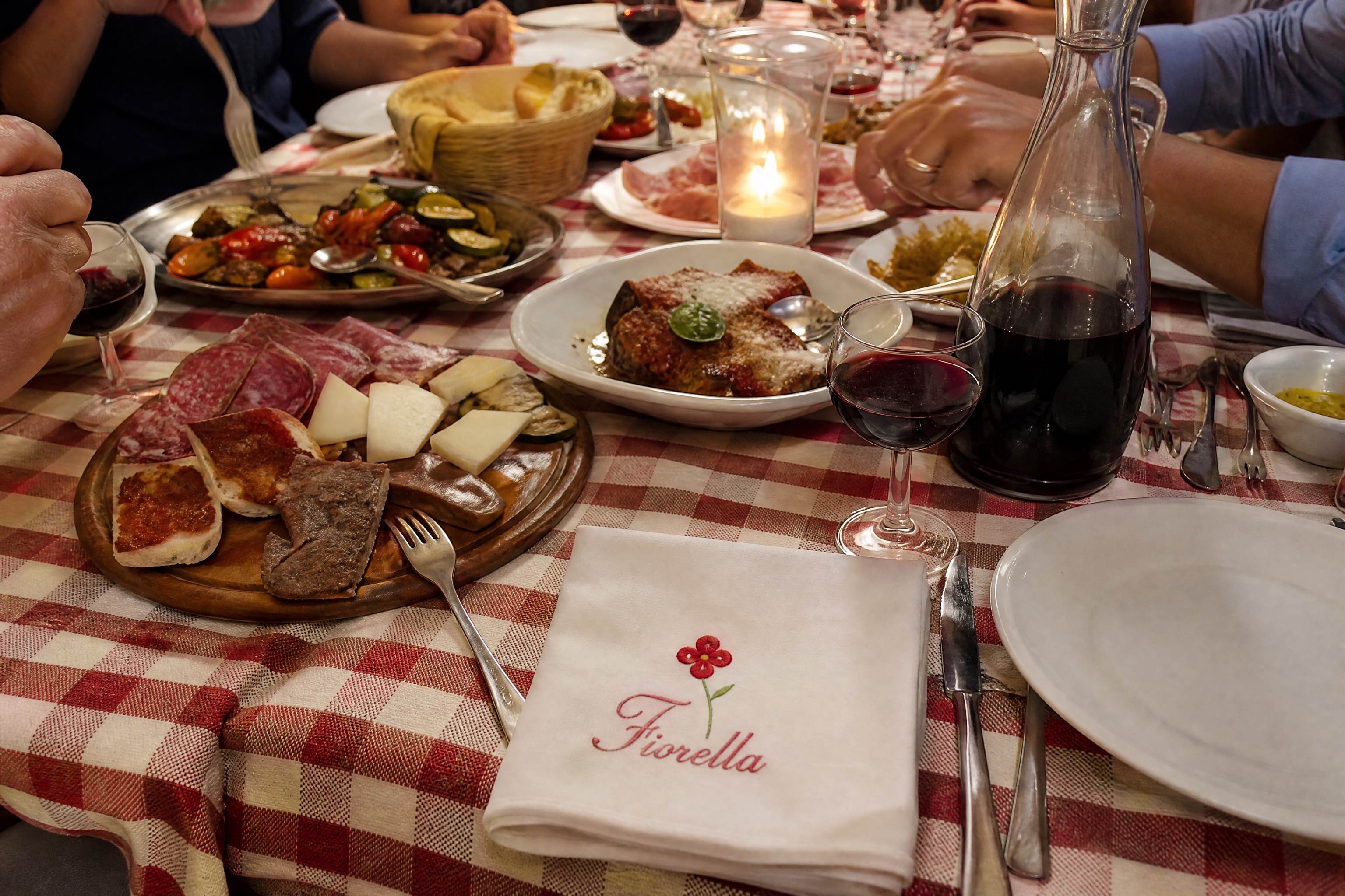 Lange gedeelde tafel van boven met antipasti en wijn, servet met geborduurd bloemetje