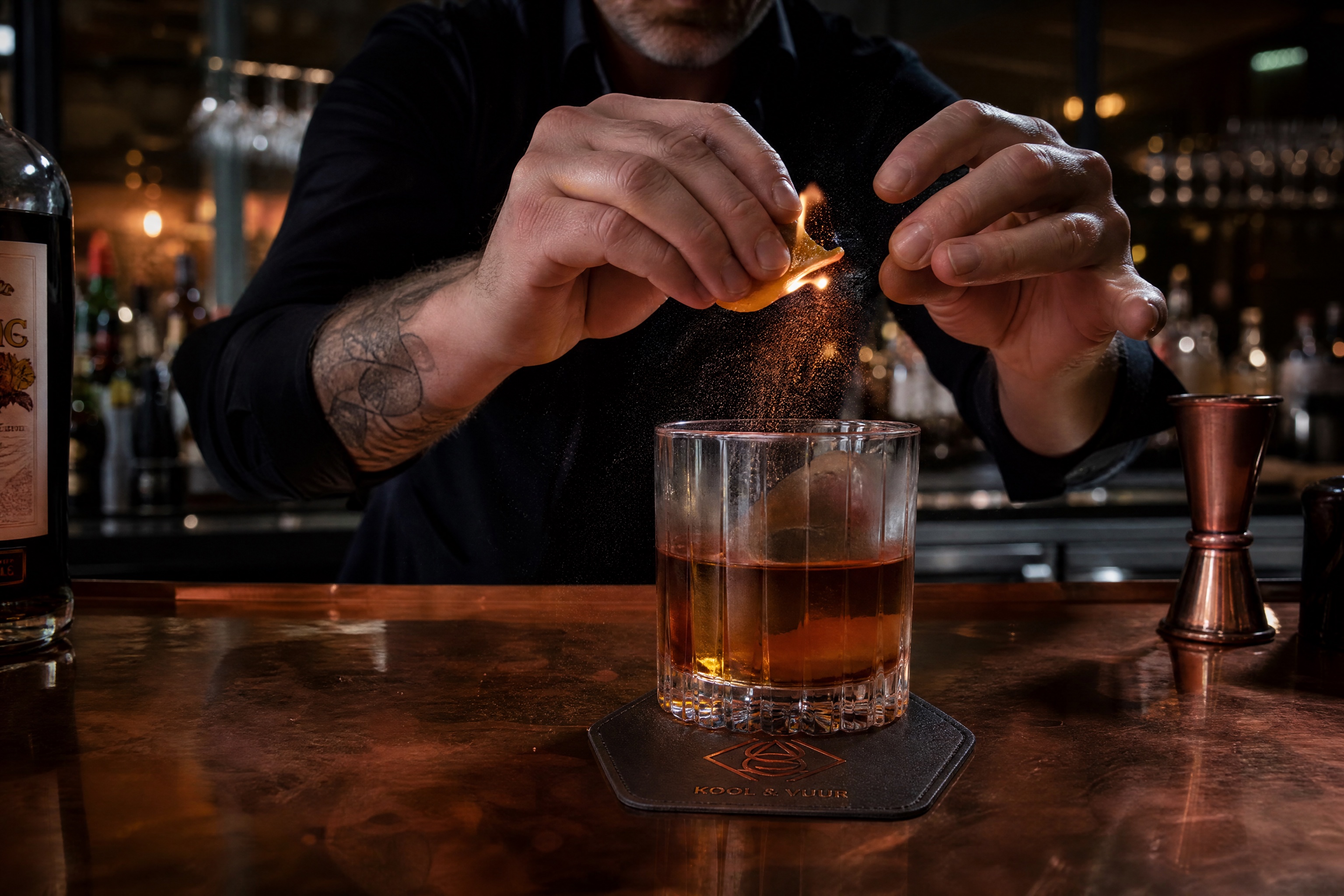 De bar: barman flambeert een sinaasappelschil boven een smoked old-fashioned
