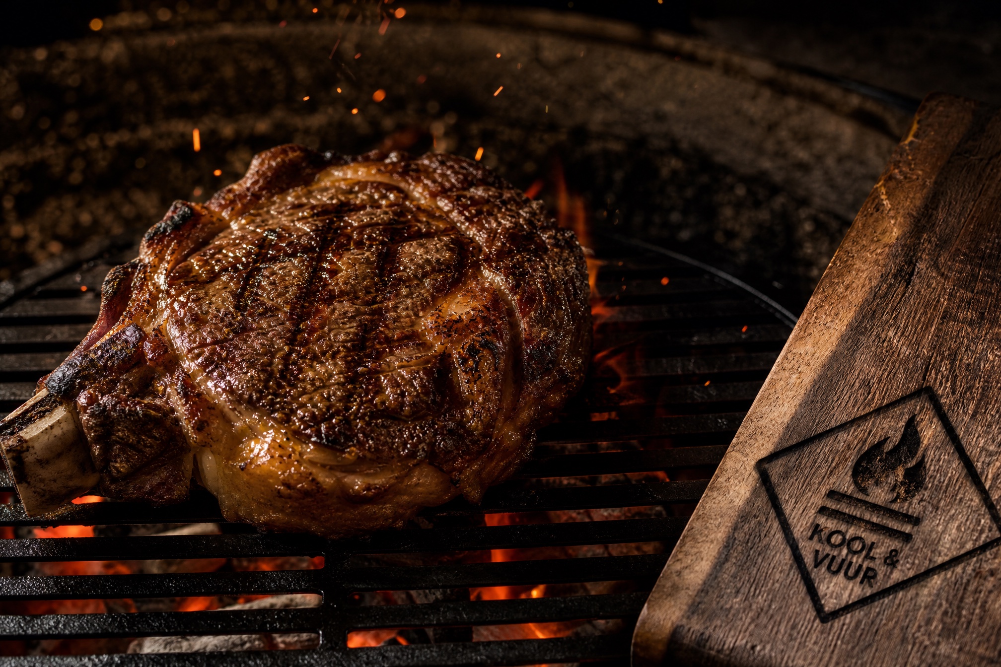 Dry-aged ribeye op de houtskoolgrill, vonken en gloed