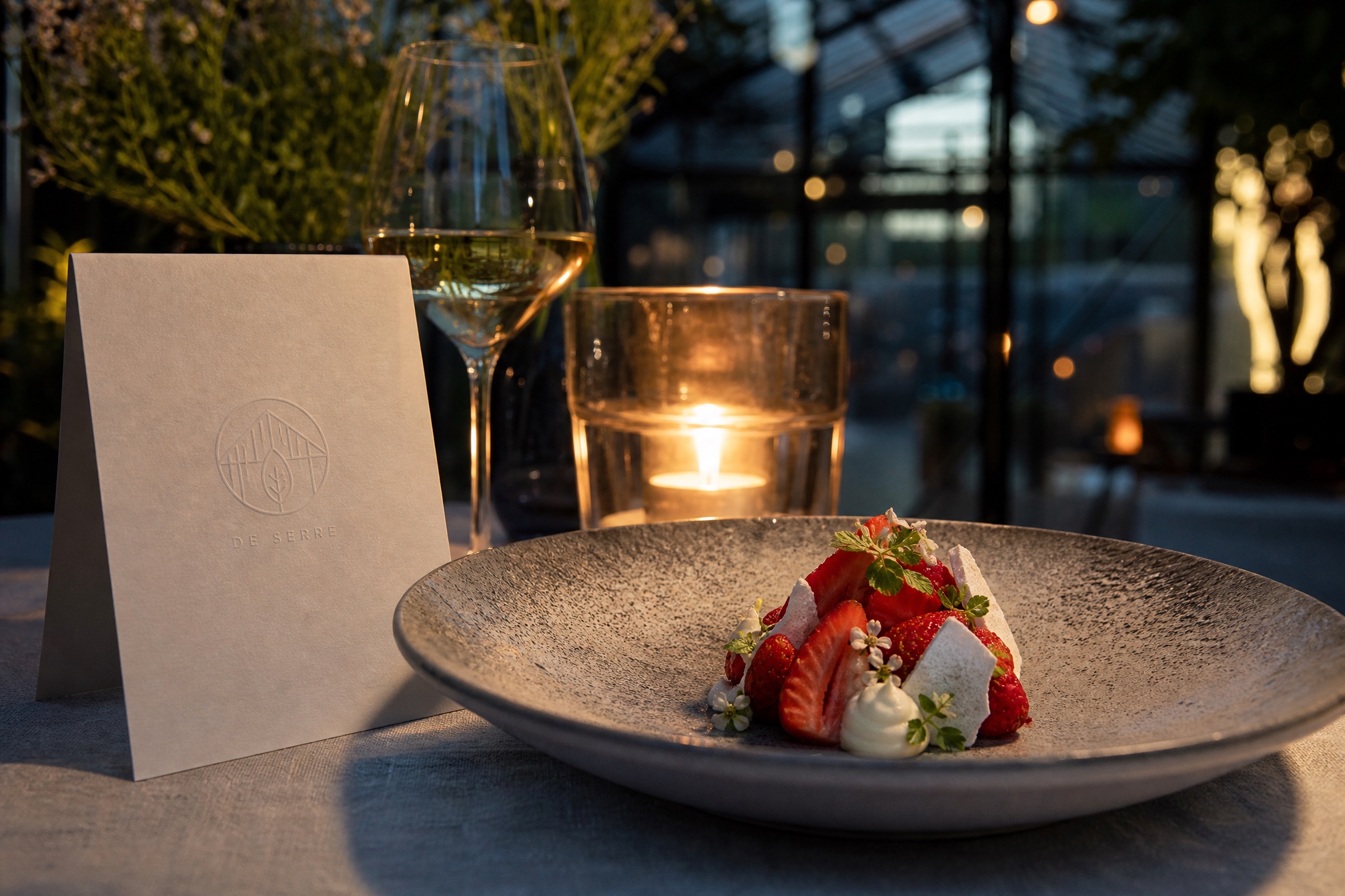 Dessert met aardbeien en eetbare bloemen, menukaart met blindgeperst monogram ernaast