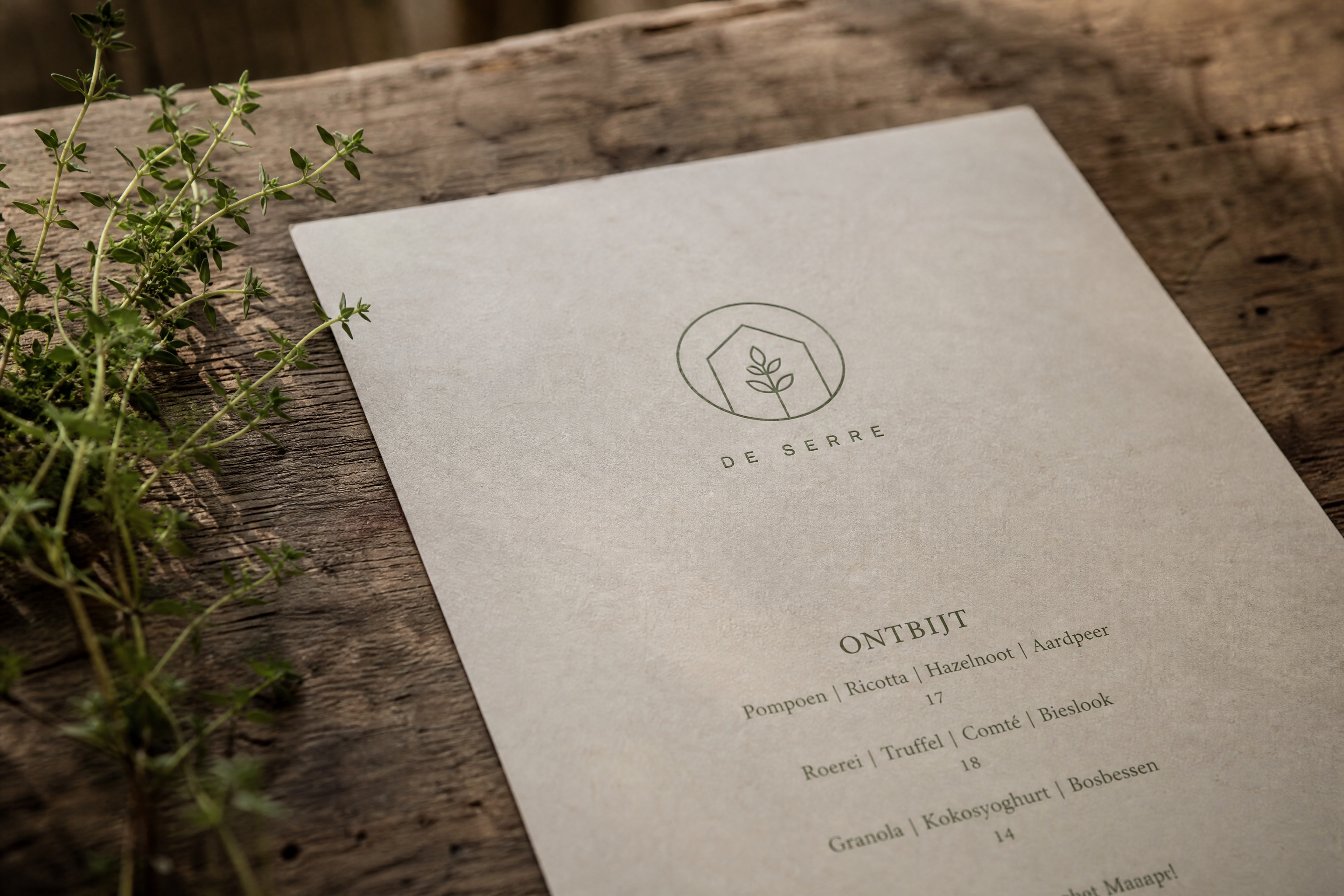 Linnen menukaart met letterpress serre-monogram op een houten tafel